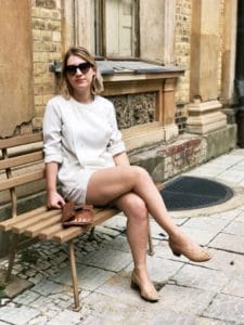 Laura wearing a secondhand blouse, old leather bag and white organic cotton shorts.