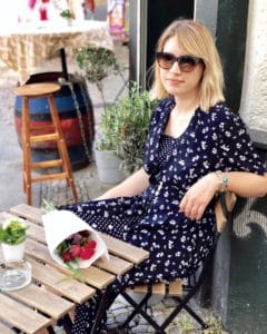 Laura sitting at a table with flowers wearing a vintage dress.