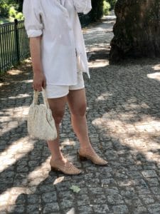 Laura wearing a white secondhand blouse, vintage bag, cotton shorts and beige shoes.